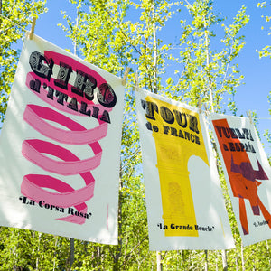 Three Cycling Grand Tour natural cotton Tea Towels: Tour de France, Giro d'Italia, and Vuelta a Espana, hanging outside on a washing line.