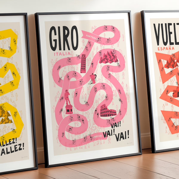 Three framed posters of cycling-themed designs propped up again a wall.