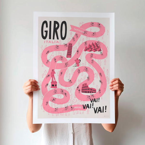 Person holding an unframed 'Giro Italia' poster, featuring a pink winding race path on a neutral background, including stylised illustrations of riders, fans and a selection of famous Italian landmarks.