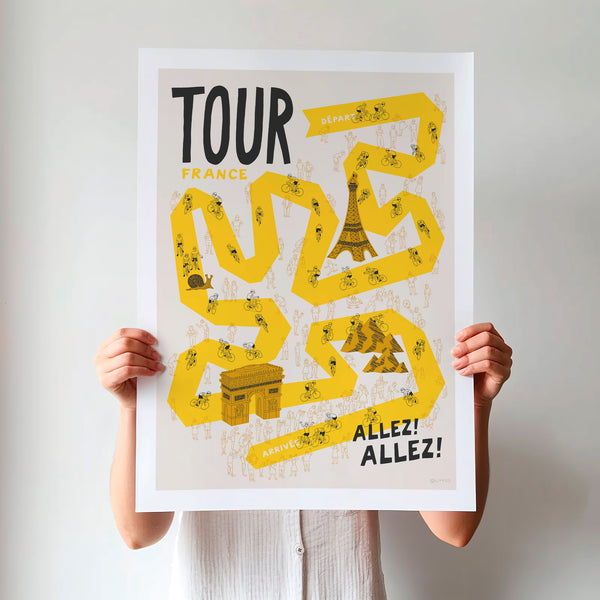 Person holding a 'Tour de France' poster with yellow route illustration and Eiffel Tower.