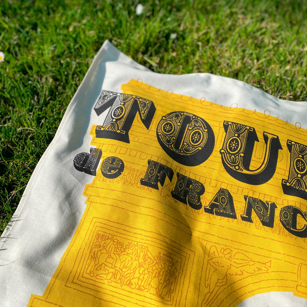 Cycling Grand Tour natural cotton tea towel, Tour de France top detail, on grass