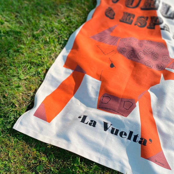 Cycling Grand Tour natural cotton tea towel, 'Vuelta a Espana', close up detail of graphic bull in orange, photographed on grass